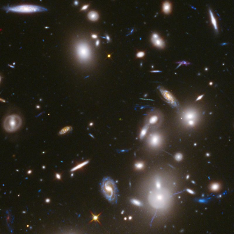 Clump of many small-appearing galaxies at all angles to each other. Some are blue, white or orange.