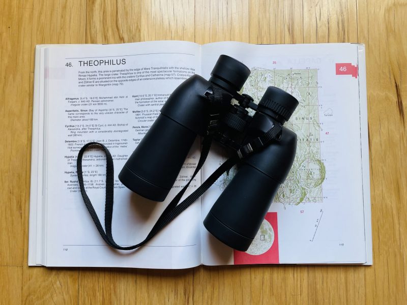 Binoculars rest on a map of the moon.