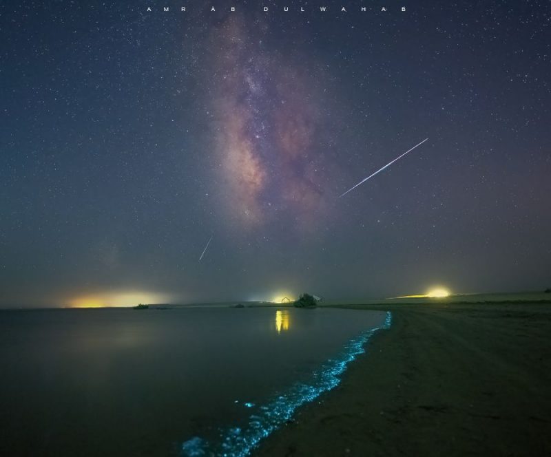 Water with light on the incoming waves plus the Milky Way and other lights behind.