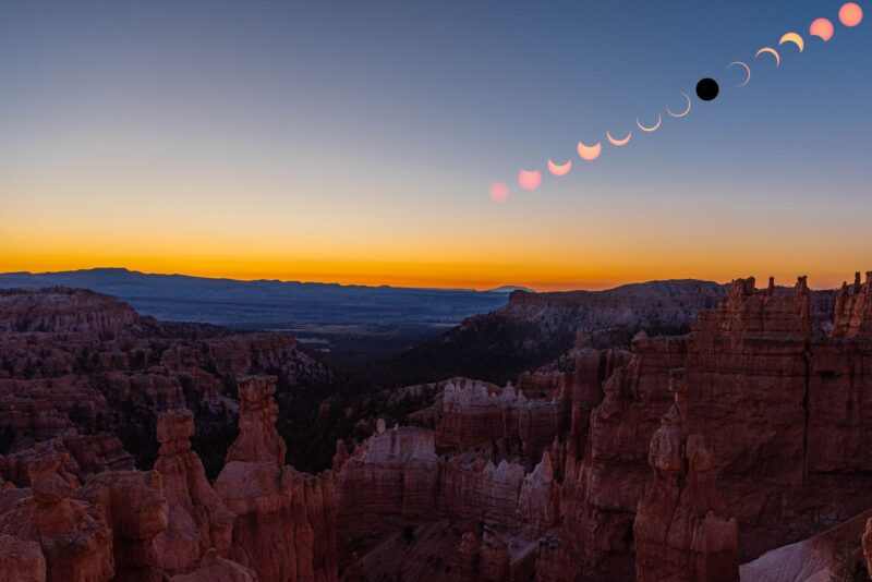 Mountain in the foreground with sharp red peaks. Orange horizon. 13 shapes for the eclipse at top right. They go from full orange sphere, to an orange ring, then a black sphere and back to orange ring and sphere.