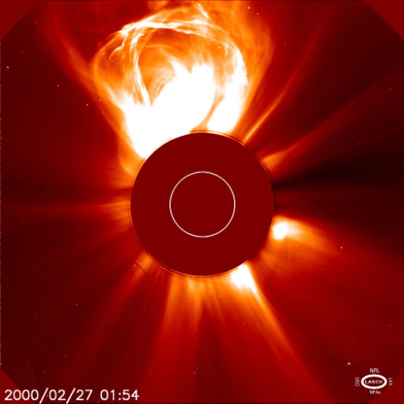 coronal mass ejections: The sun, with the center blocked for visibility, and a huge bright circular flare coming out from near the top.