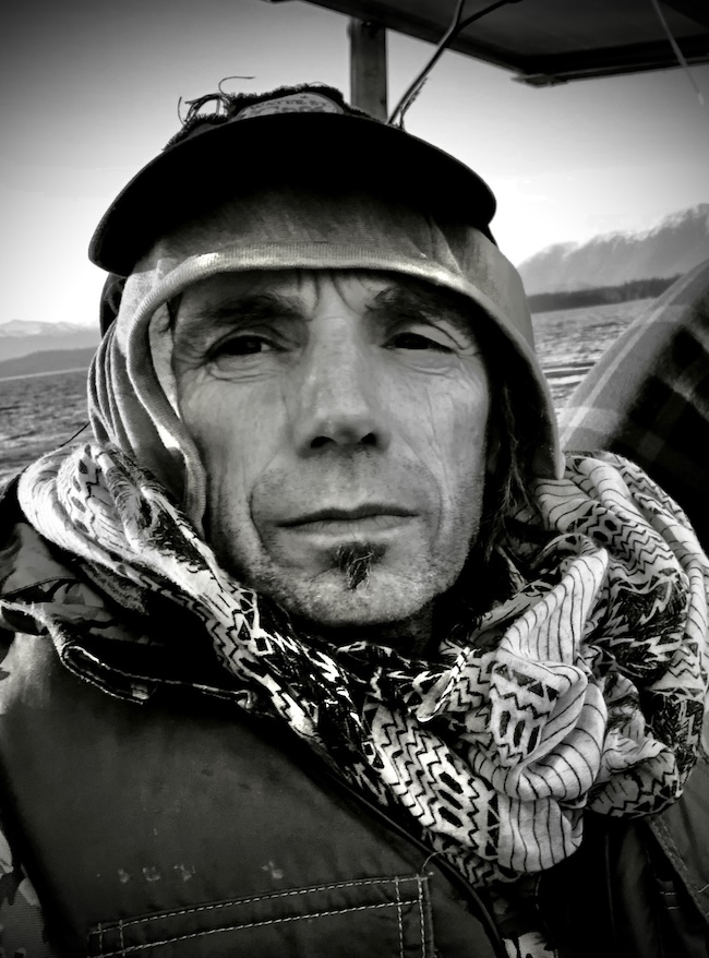Black and white photo of a man bundled up in winter gear on a boat.