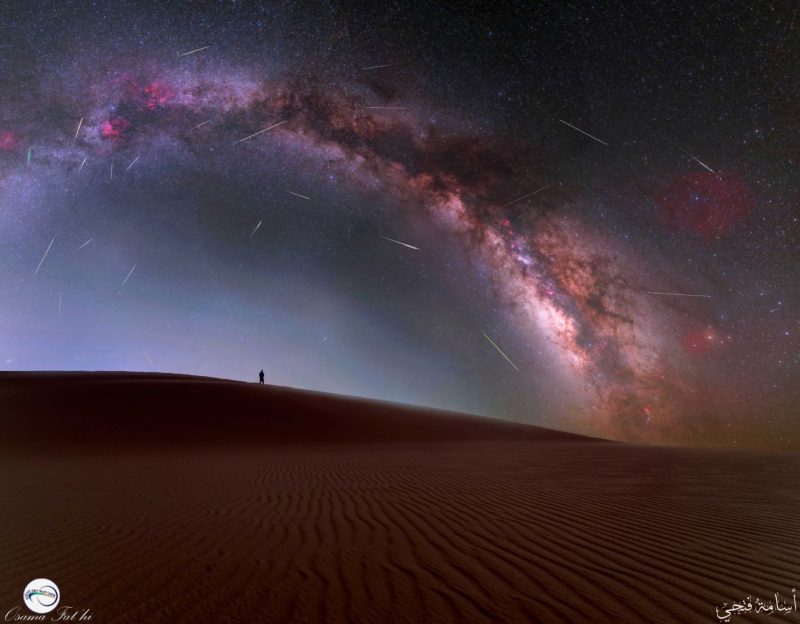 Arching Milky Way with long dark swaths along it, and lots of thin, bright meteor streaks.