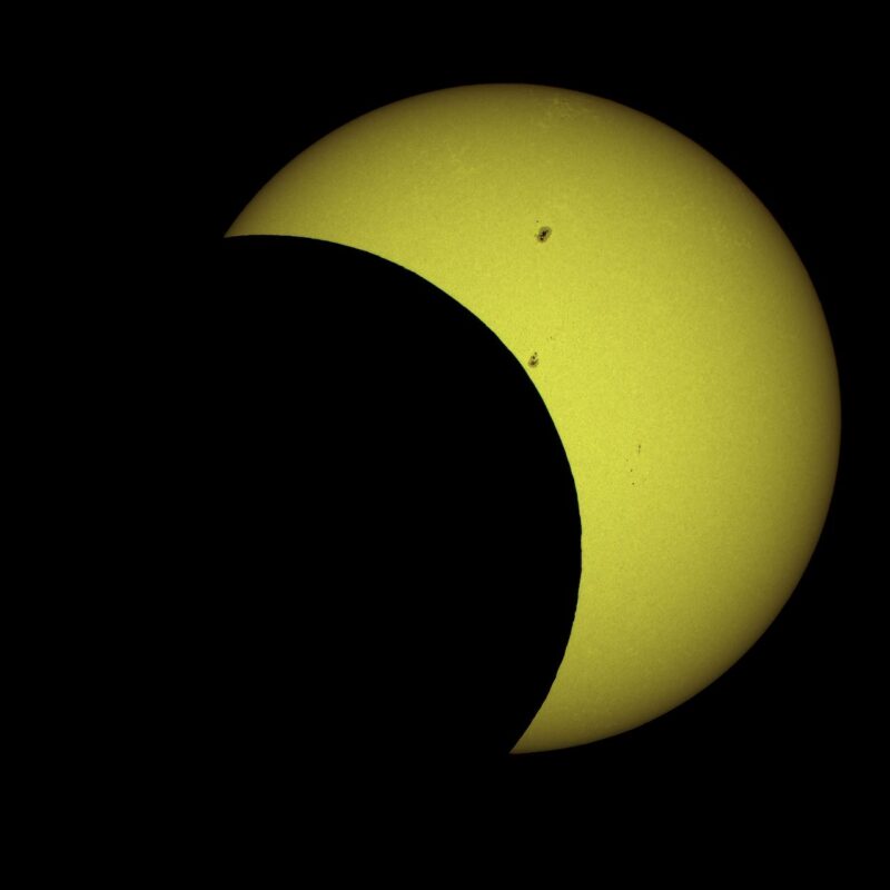 Thick yellow crescent, clearly part of a sphere, with 2 black spots on it.