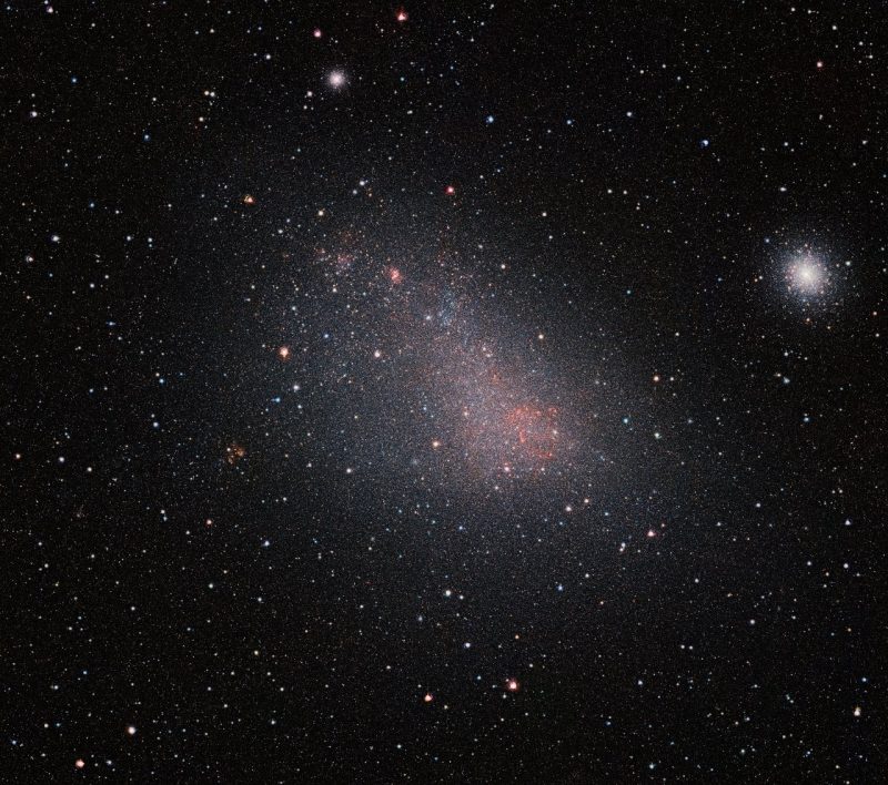 Hazy cluster of reddish and white stars, with tight cluster ball of stars to the right.