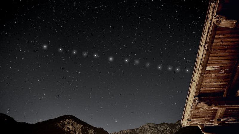 A line of 13 evenly spaced white dots across a starry sky above mountains.