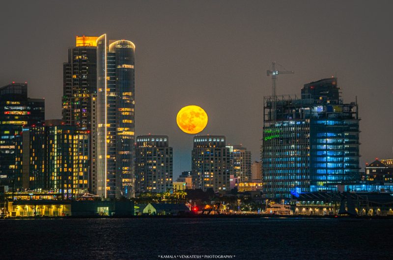 Full golden supermoon over night cityscape.