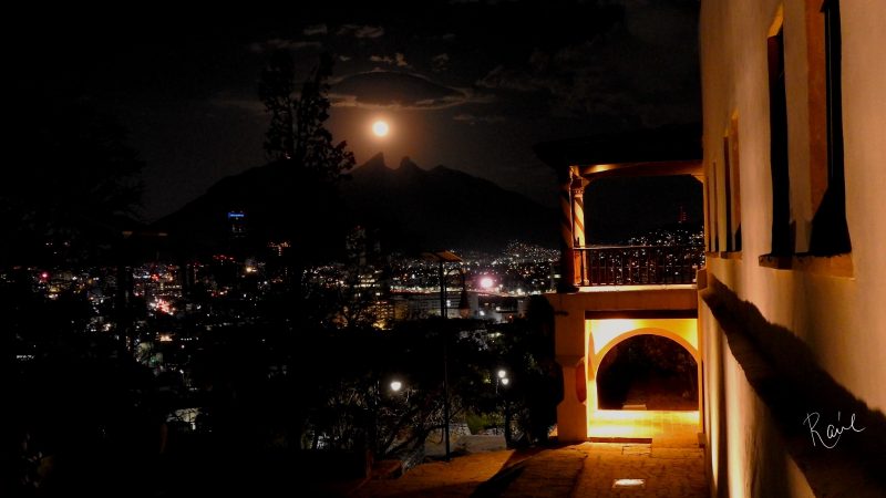 Full moon in distant cloudy sky from city balcony.