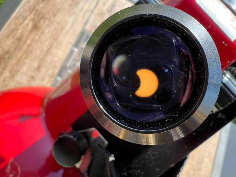 A circular lens with a slightly fuzzy. thick orange crescent on a dark background.
