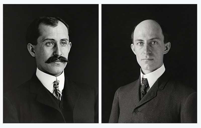 Black and white portraits of 2 men in suits, one with a big mustache and the other balding.