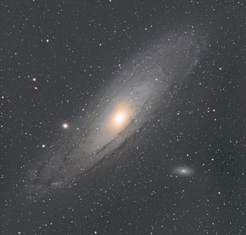 Oblique view of large, yellowish, fuzzy disk-shaped object with a bright core, in scattered star field.