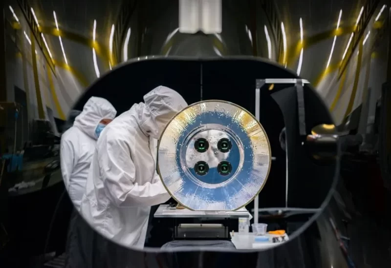 Scientists in laboratory clothing working on a machine.